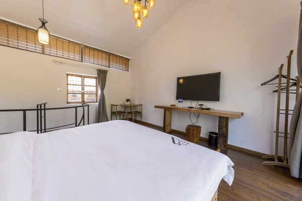 A bedroom with a large bed, a desk, a chair, a TV, and a wardrobe. - Jiannanshan Garden Homestay (Kunming)