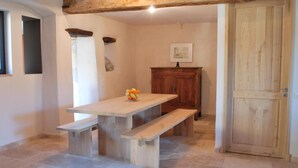 A dining area with a wooden table and benches, a wooden cabinet, and a door. - Gite Le Roucayral– Superb view over St Cirq Lapopie – 2 air-conditioned bedrooms (Tour de Faure)