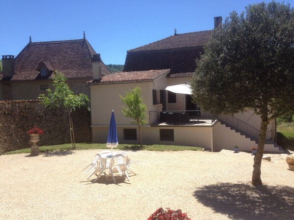 A house with a gravel patio, a blue umbrella, and a tree. - Gite Le Roucayral– Superb view over St Cirq Lapopie – 2 air-conditioned bedrooms (Tour de Faure)