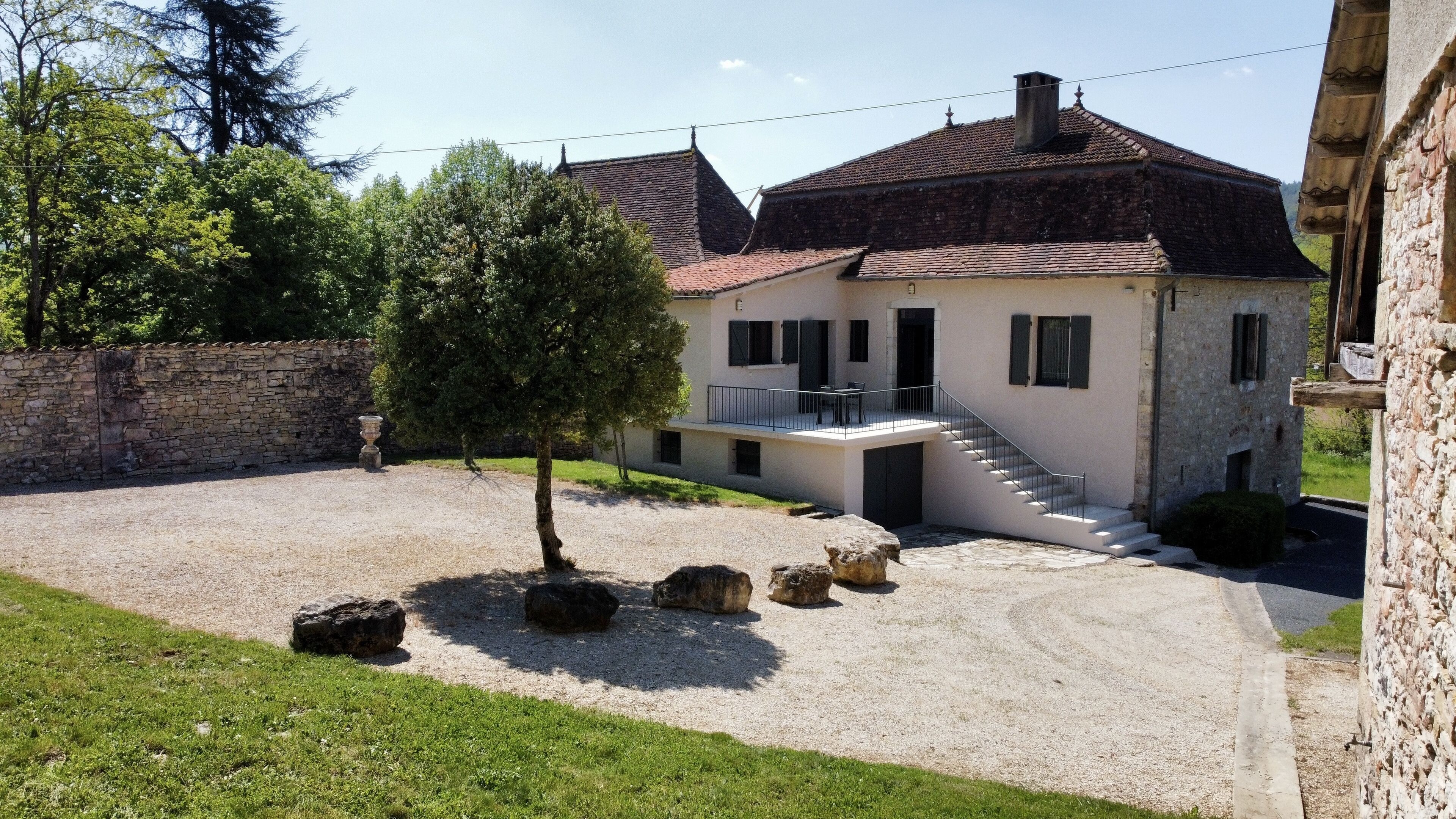 A two-story house with a stone facade, a balcony, and a gravel driveway.
