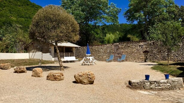 A stone building with a covered patio, outdoor seating, and a stone wall. - Gite Le Roucayral– Superb view over St Cirq Lapopie – 2 air-conditioned bedrooms (Tour de Faure)