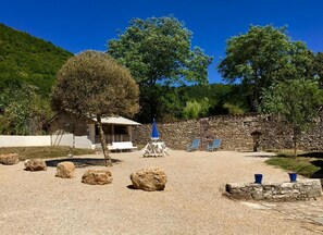 A stone building with a covered patio, outdoor seating, and a stone wall. - Gite Le Roucayral– Superb view over St Cirq Lapopie – 2 air-conditioned bedrooms (Tour de Faure)