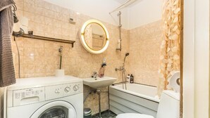 A compact bathroom with a washing machine, sink, toilet, and a shower area. - Go Happy Home Apartment Mikonkatu 18 (Helsinki)