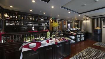 A bar area with shelves of liquor bottles, a buffet with various dishes, and a patterned floor.