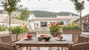 An outdoor patio with a wooden table and chairs, surrounded by potted plants and flowers. - Manuel de La Capilla (Cambil)