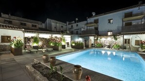 A courtyard with a swimming pool, stone walls, and outdoor seating areas. - Manuel de La Capilla (Cambil)