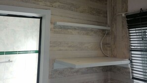 Une pièce avec un sol carrelé, une porte blanche, un plafond doté d’un éclairage encastré et une fenêtre avec des stores.