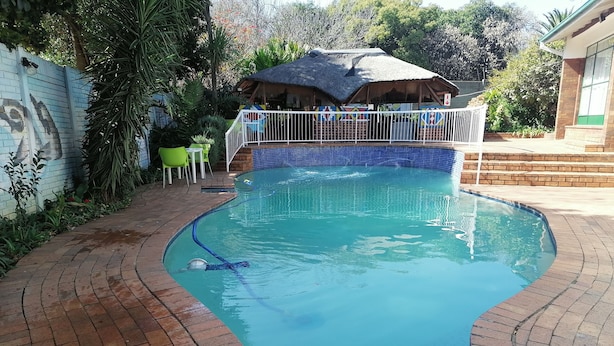 Une piscine dont le bord est revêtu de carreaux, entourée d’une terrasse en briques et d’une clôture.