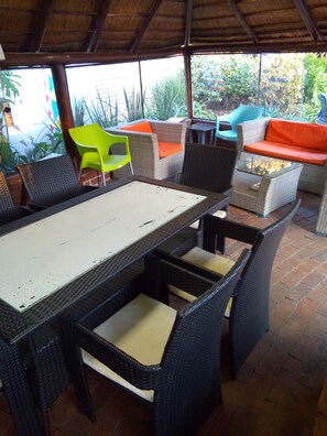 Un espace extérieur aménagé en terrasse, avec des meubles en osier, notamment une table, des chaises et un canapé.