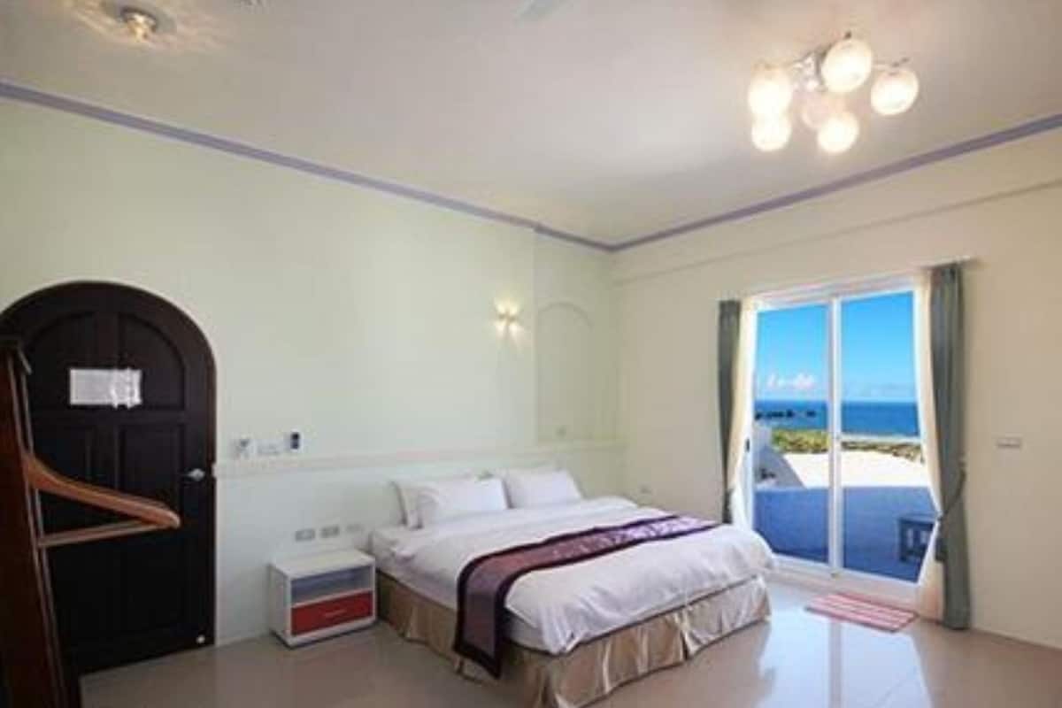 Une chambre à coucher avec un lit, une table de chevet, une commode et une porte.