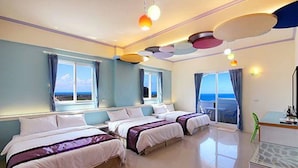 Quarto de hotel com duas camas, janelas amplas e vista para o mar.