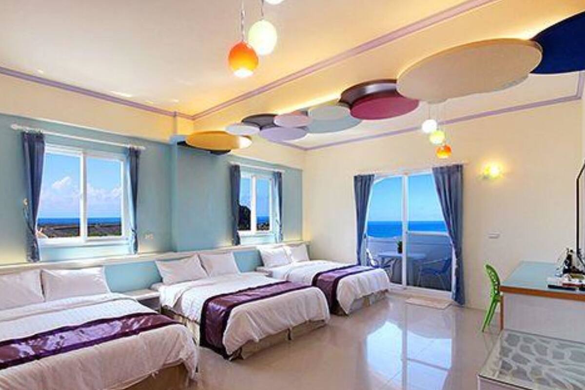 Une chambre d’hôtel avec deux lits, de grandes fenêtres et une vue sur la mer.