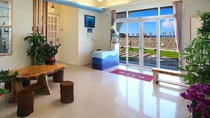 Uma sala de estar moderna com um banco de madeira, uma janela grande com vista para a praia e um teto com design ondulado.