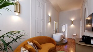 A modern living room with a curved sofa, a round ottoman, and a small table. - Ricasoli Garden Relais (Florence)