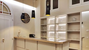 A kitchen with a wooden countertop, a clock, pendant lights, and shelves with wine glasses. - Ricasoli Garden Relais (Florence)