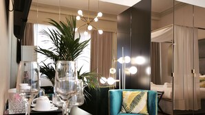 A modern hotel room with a dining area featuring a glass table, wine glasses, and a decorative plant. - Ricasoli Garden Relais (Florence)