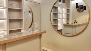 A modern bathroom with a vanity, a round mirror, and shelves with glassware. - Ricasoli Garden Relais (Florence)