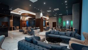 Un vestíbulo moderno con asientos cómodos, una recepción y un escenario con iluminación verde.