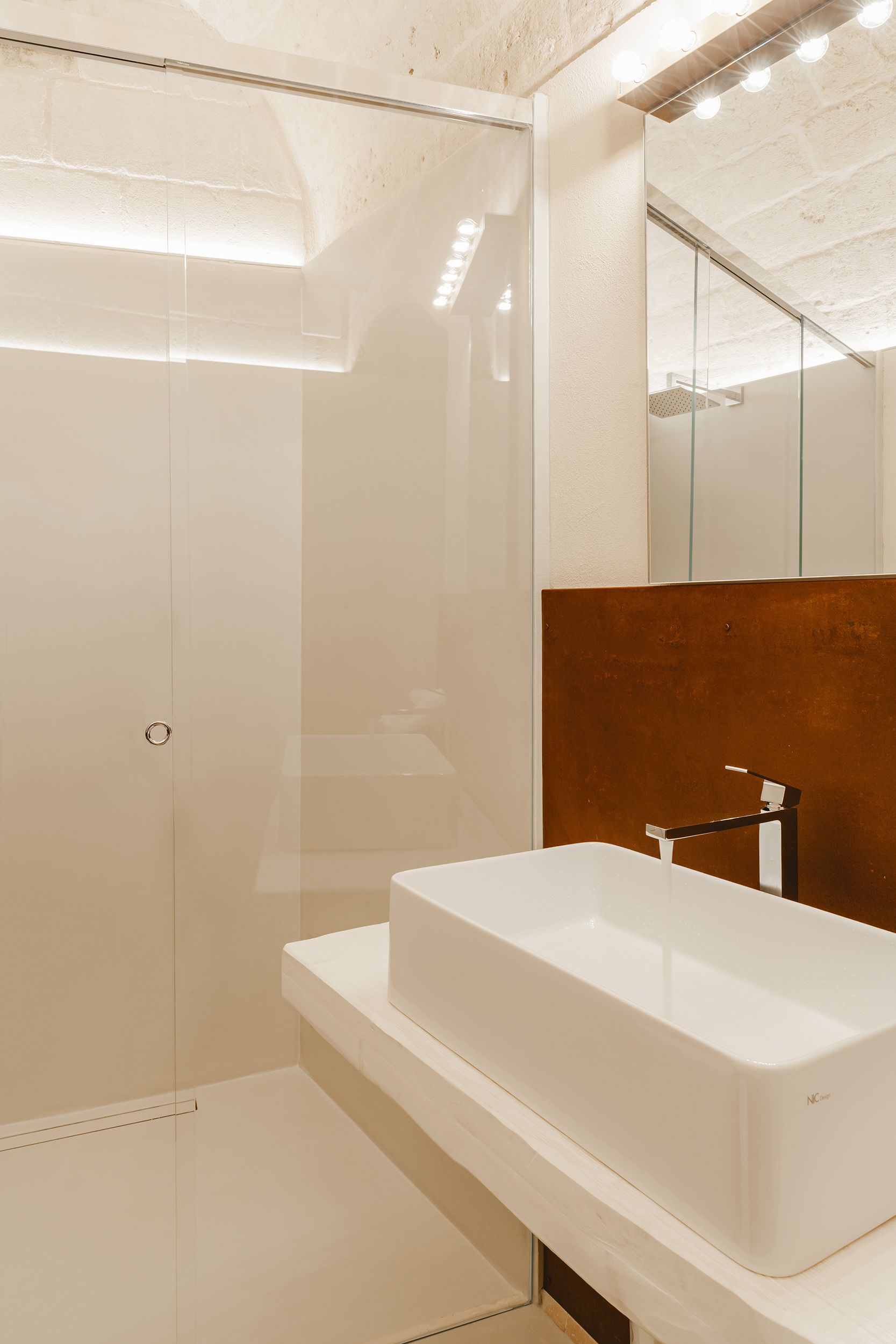 Une salle de bain moderne avec une douche à parois de verre, un lavabo blanc et un grand miroir.