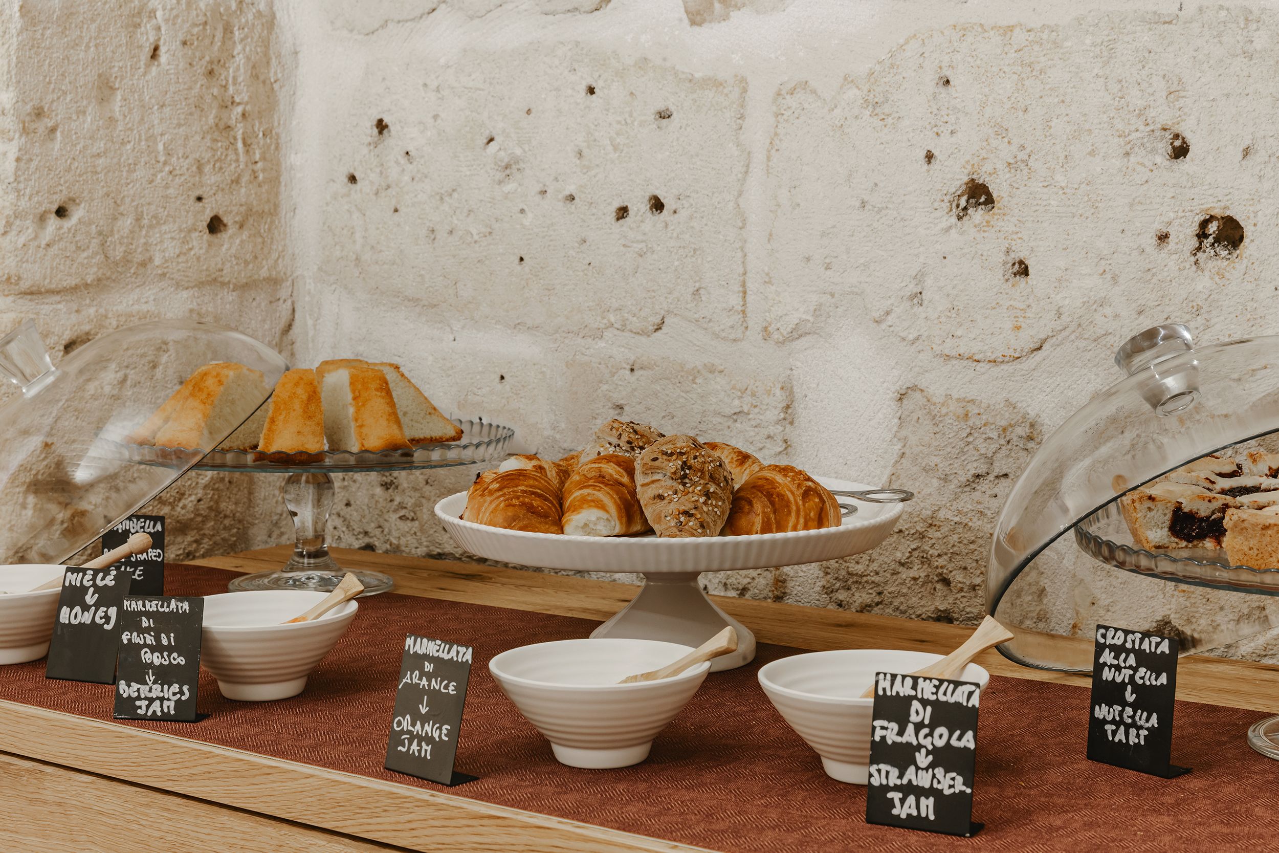 A bakery display with various pastries and desserts, including croissants and tarts, with labels indicating flavors like strawberry and hazelnut.