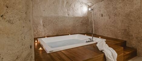 A modern bathroom with a freestanding bathtub, wooden steps, and candles.