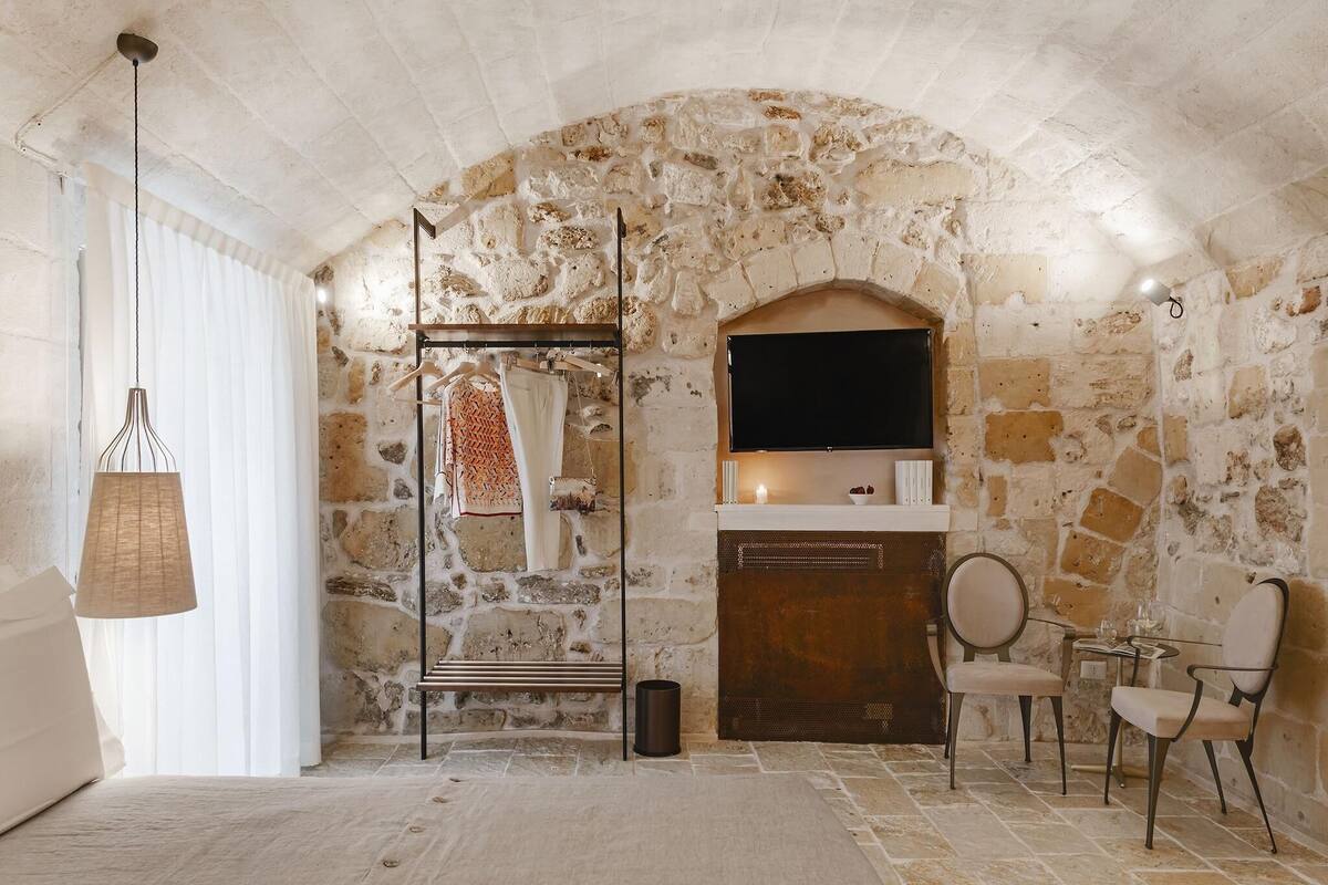 A stone-walled room with a fireplace, a hanging light fixture, and a seating area.