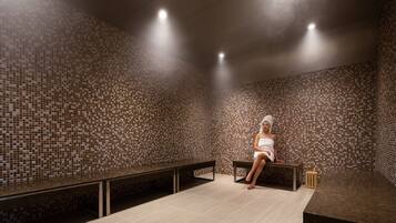 Una stanza della spa con pareti rivestite di mosaici, una panca e un lettino da massaggio.