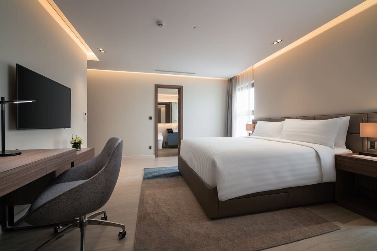 Ett modernt hotellrum med en stor säng, ett skrivbord, en stol och en TV.