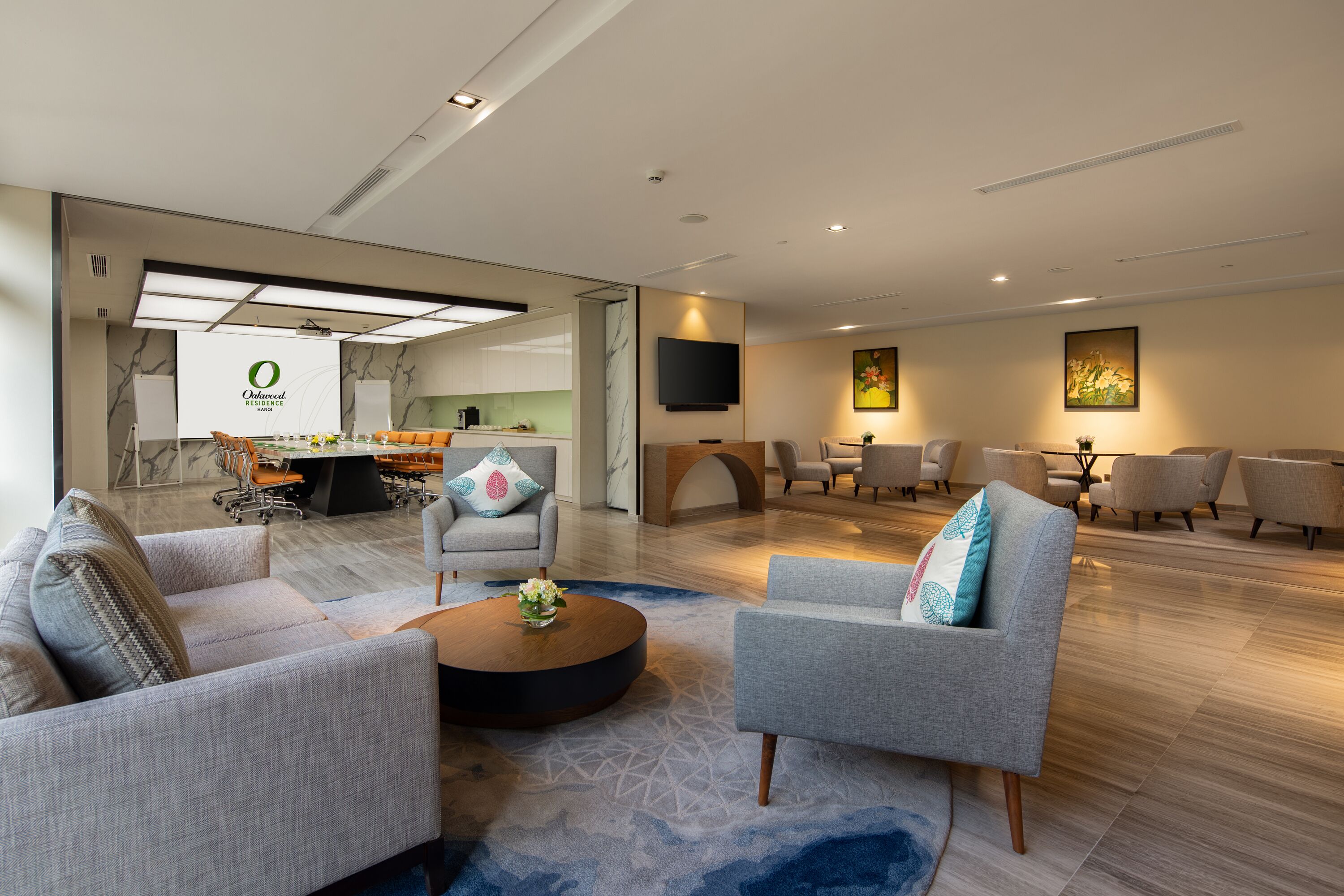 A modern living room with grey sofas, a coffee table, and a dining area with chairs.