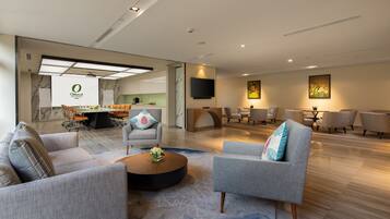 Ein modernes Wohnzimmer mit grauen Sofas, einem Couchtisch und einem Essbereich mit Stühlen.