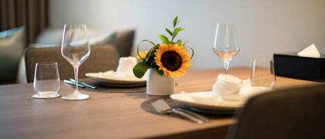 A dining table set with wine glasses, a vase with a sunflower, and a napkin holder.