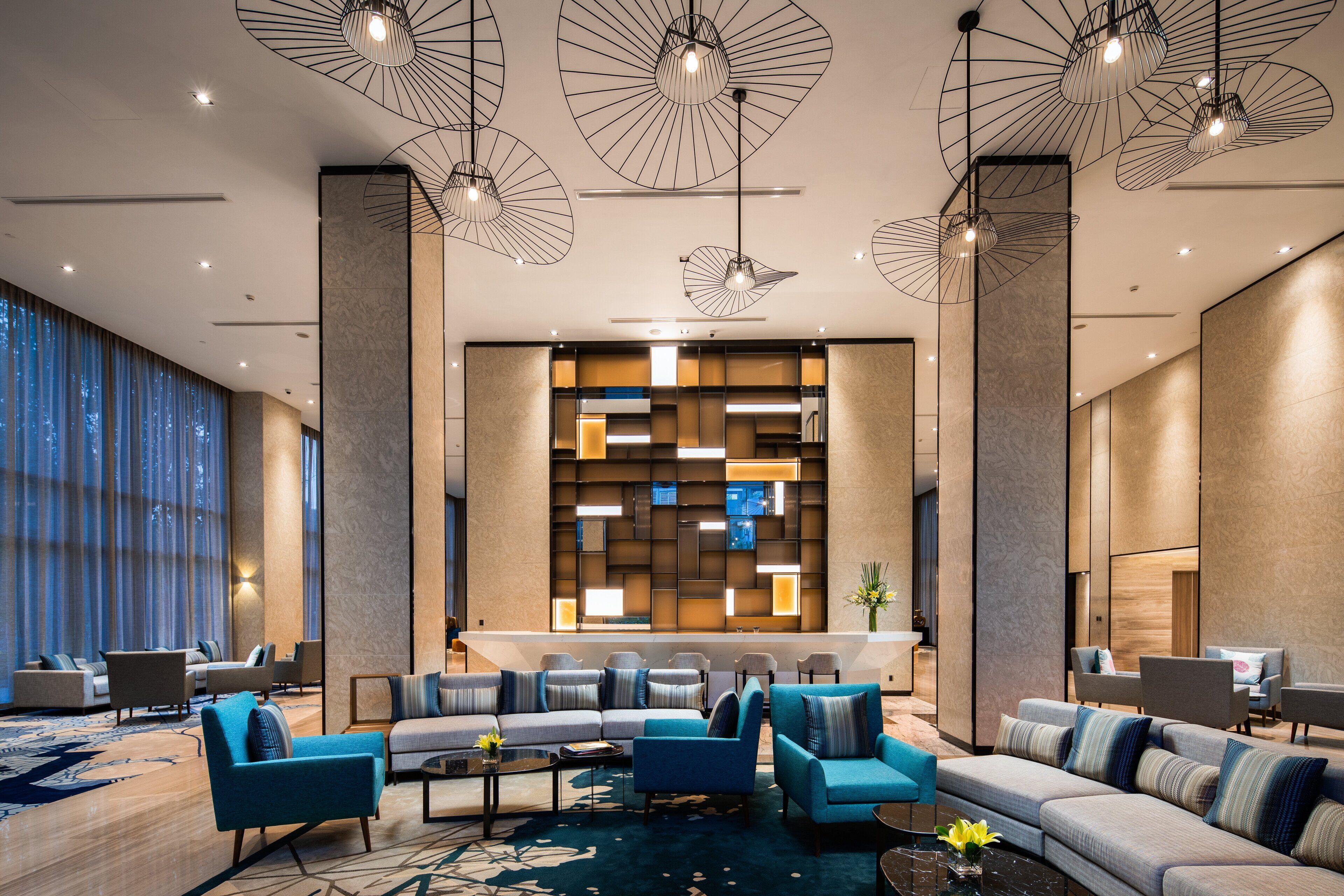 A modern lobby with a seating area, large windows, and a decorative wall with integrated lighting.