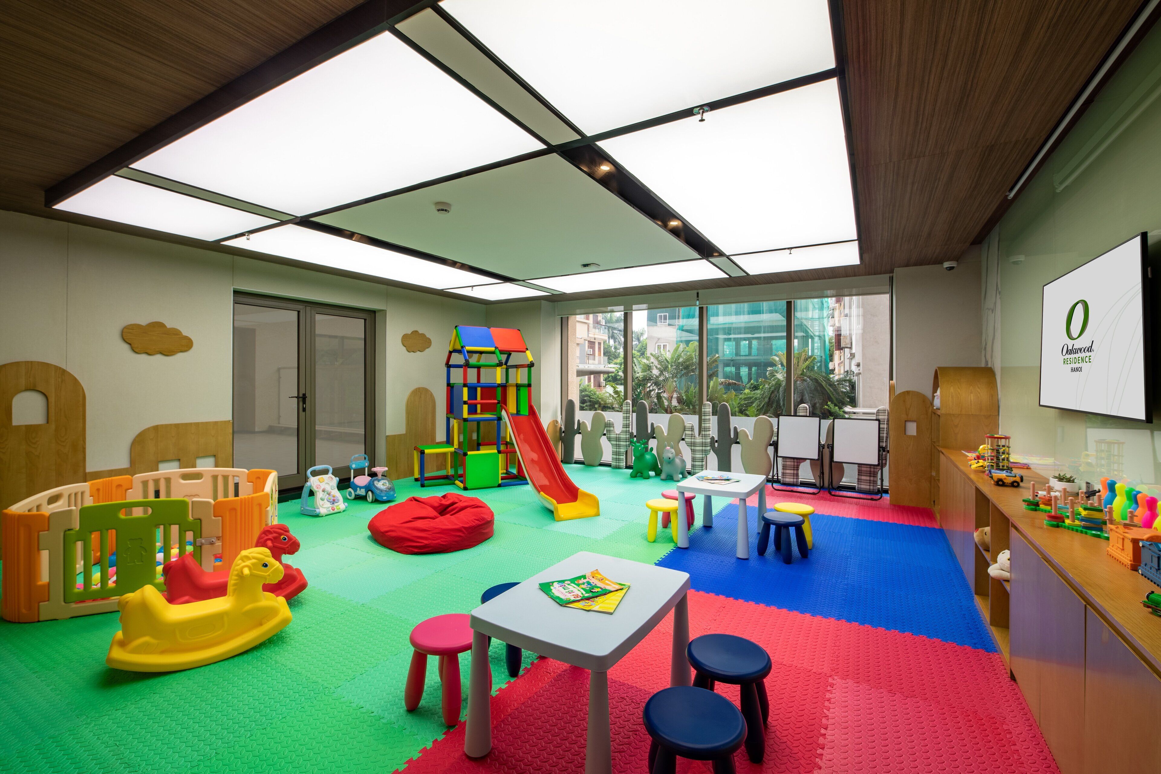 Ein Kinderspielzimmer mit Rutsche, Spielgeräten und einem Tisch mit Stühlen.