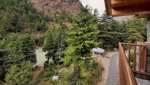 Paisaje montañoso con bosque denso y un edificio pequeño cerca de una carretera.