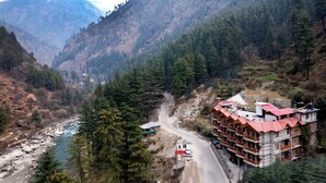 Un paisaje montañoso con un río, una carretera y un edificio con tejado rojo.