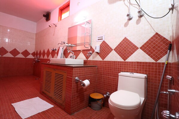 A bathroom with a red and white checkered tile pattern, a sink, a toilet, and a shower.