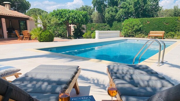 A poolside area with lounge chairs, a book, and a glass of wine. - Private pool in Mediterranean house on the French Riviera (Roquebrune-sur-Argens)