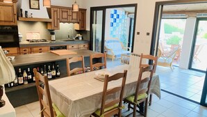 A modern kitchen with wooden cabinets, a built-in oven, and a dining area with a table and chairs. - Private pool in Mediterranean house on the French Riviera (Roquebrune-sur-Argens)