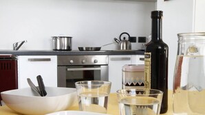 Una cucina con un fornello, pentole, un bollitore e una bottiglia di vino.