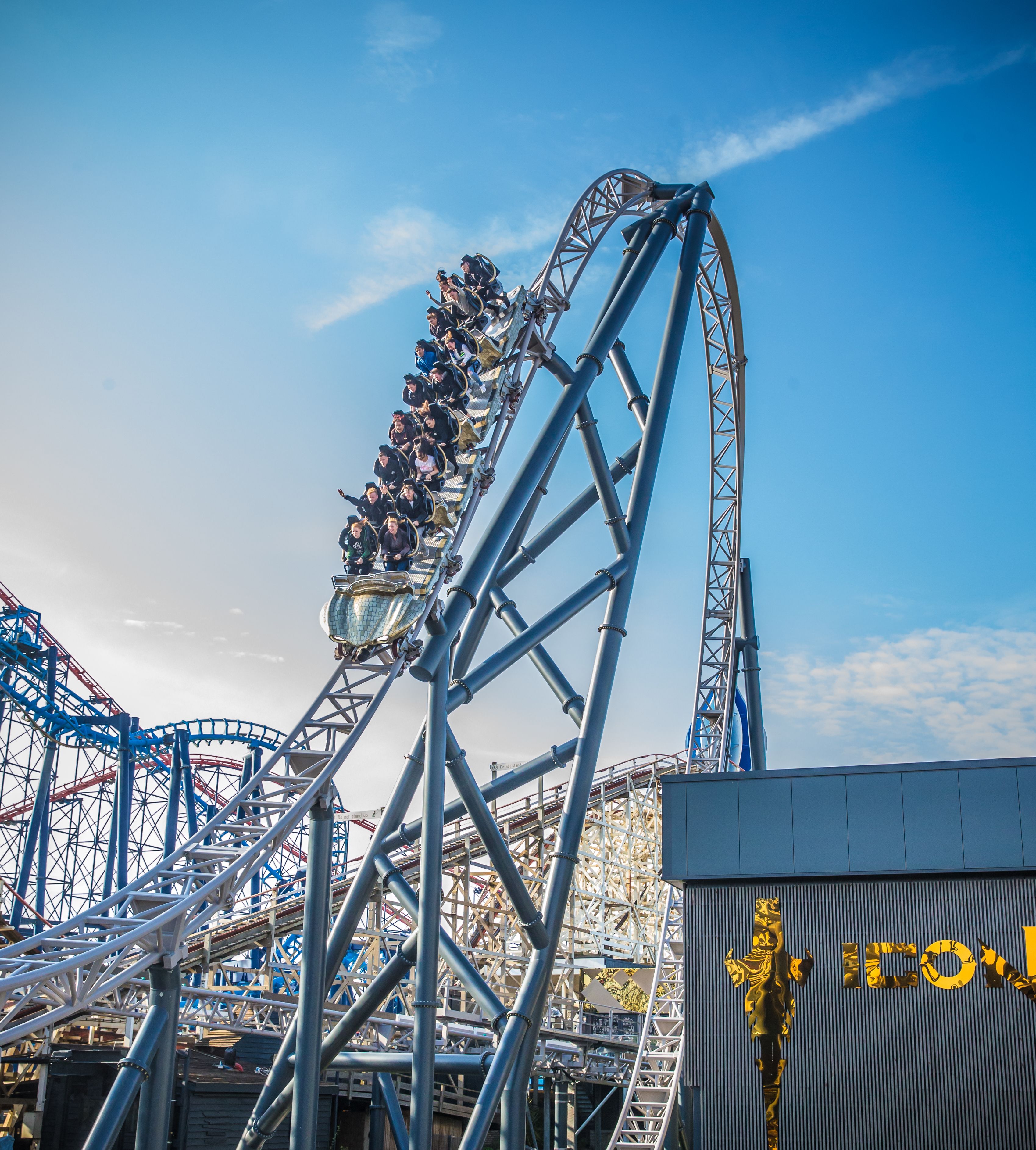 Een achtbaan met passagiers, onderdeel van een grotere attractie in een pretpark.