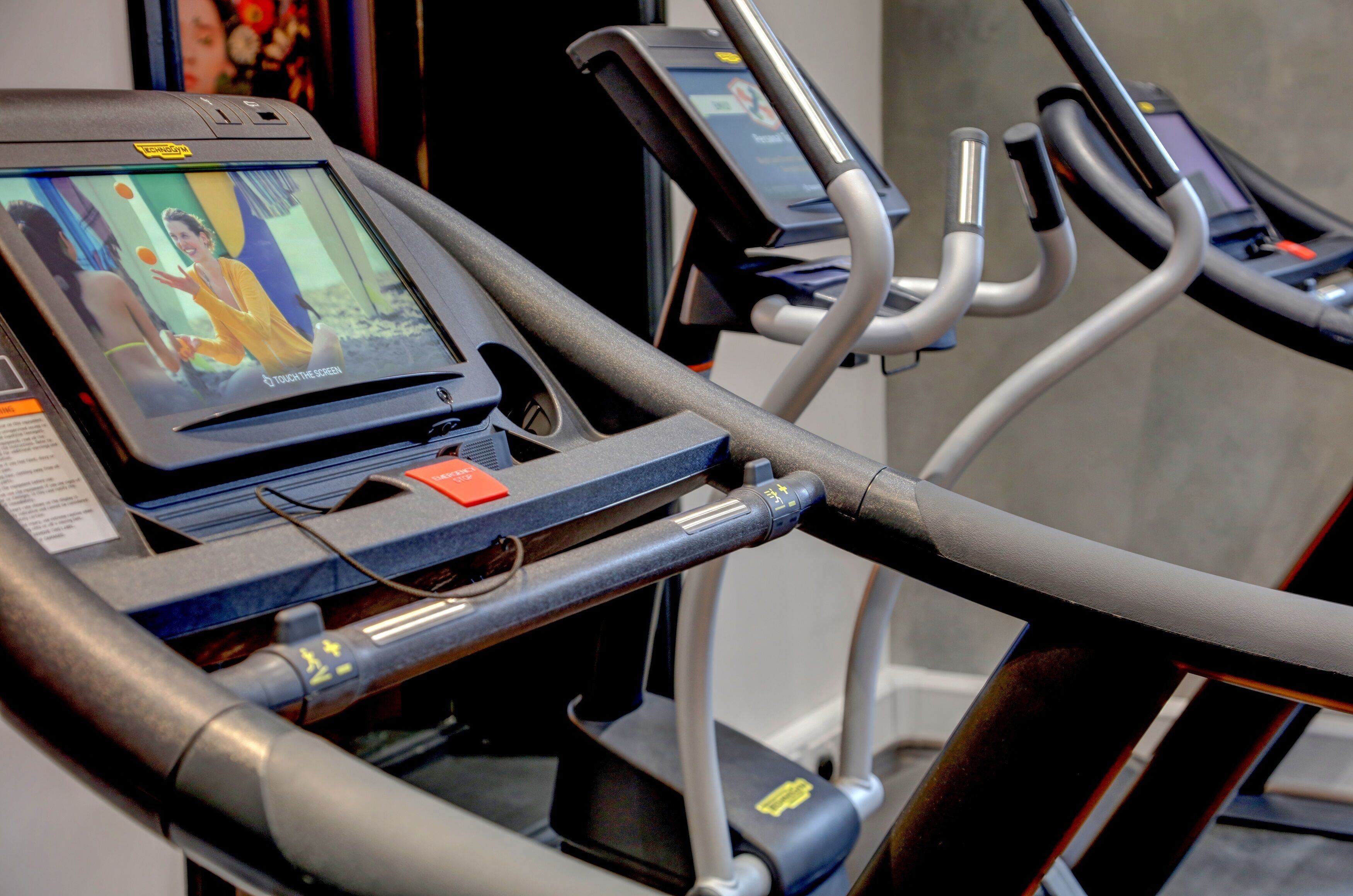 A treadmill with a digital screen displaying a woman in a yellow outfit.