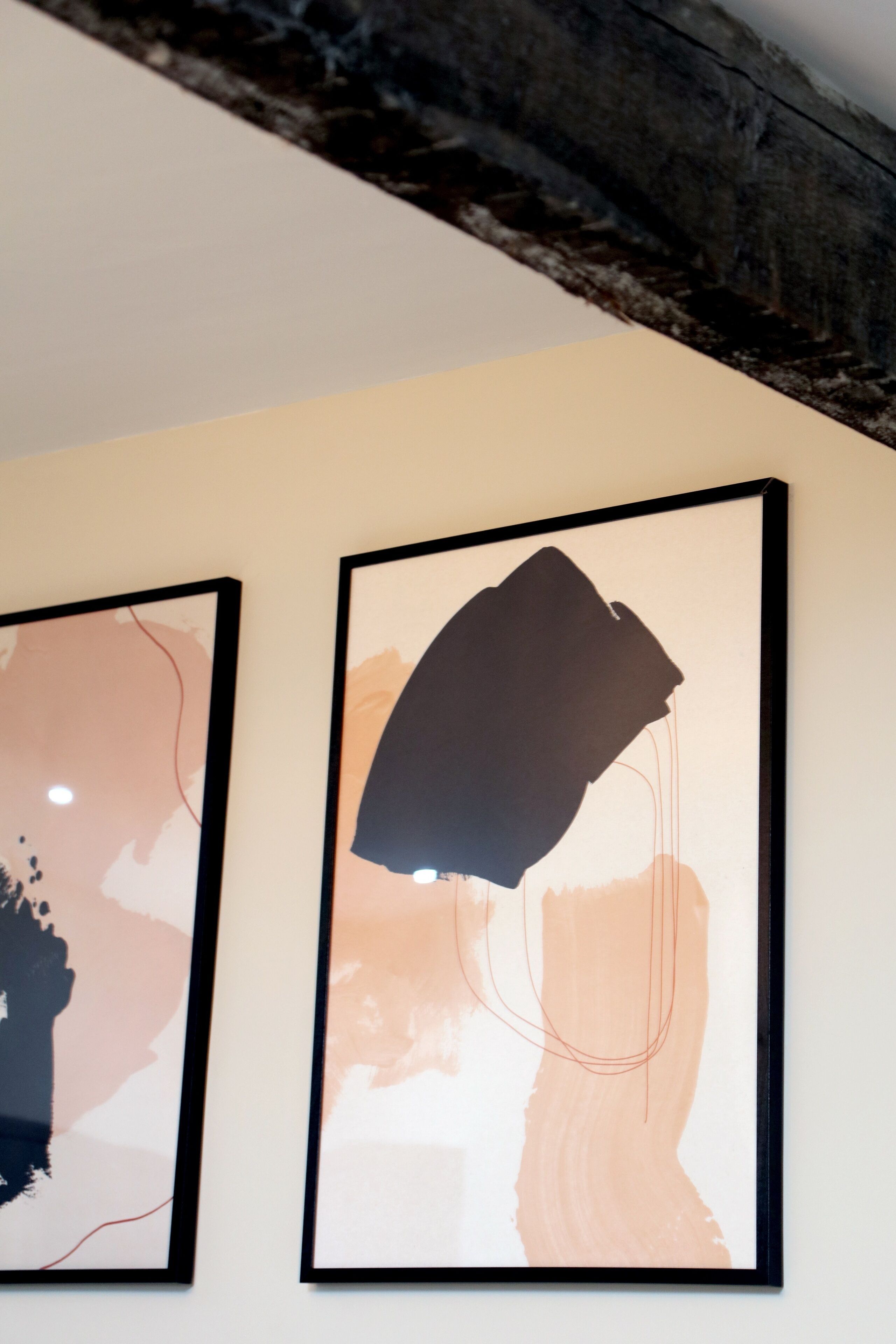 Twee abstracte schilderijen in lijsten aan een muur.