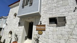 Un edificio con fachada de piedra, un letrero que dice "TasAda" y una pequeña entrada con escalones.