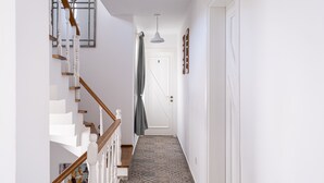 Un pasillo con piso estampado, paredes blancas, una escalera de madera y una puerta numerada con el número 3.