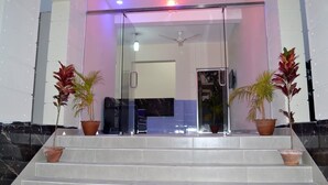A modern entrance with glass doors, a ceiling fan, and potted plants on the steps. - Somudra Bari Resort (Kalapara)