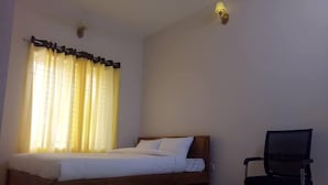 A bedroom with a wooden bed, a chair, and a window with yellow curtains. - Somudra Bari Resort (Kalapara)