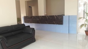 A reception area with a marble reception desk, a black leather sofa, and a potted plant. - Somudra Bari Resort (Kalapara)