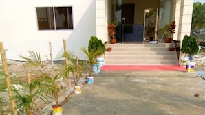 A building entrance with a red carpet, potted plants, and a concrete ground. - Somudra Bari Resort (Kalapara)