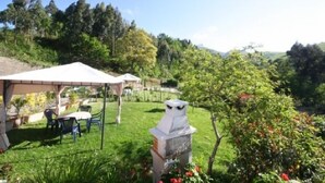 Un jardín con un pabellón, mobiliario para exteriores y una estatua decorativa de un búho.