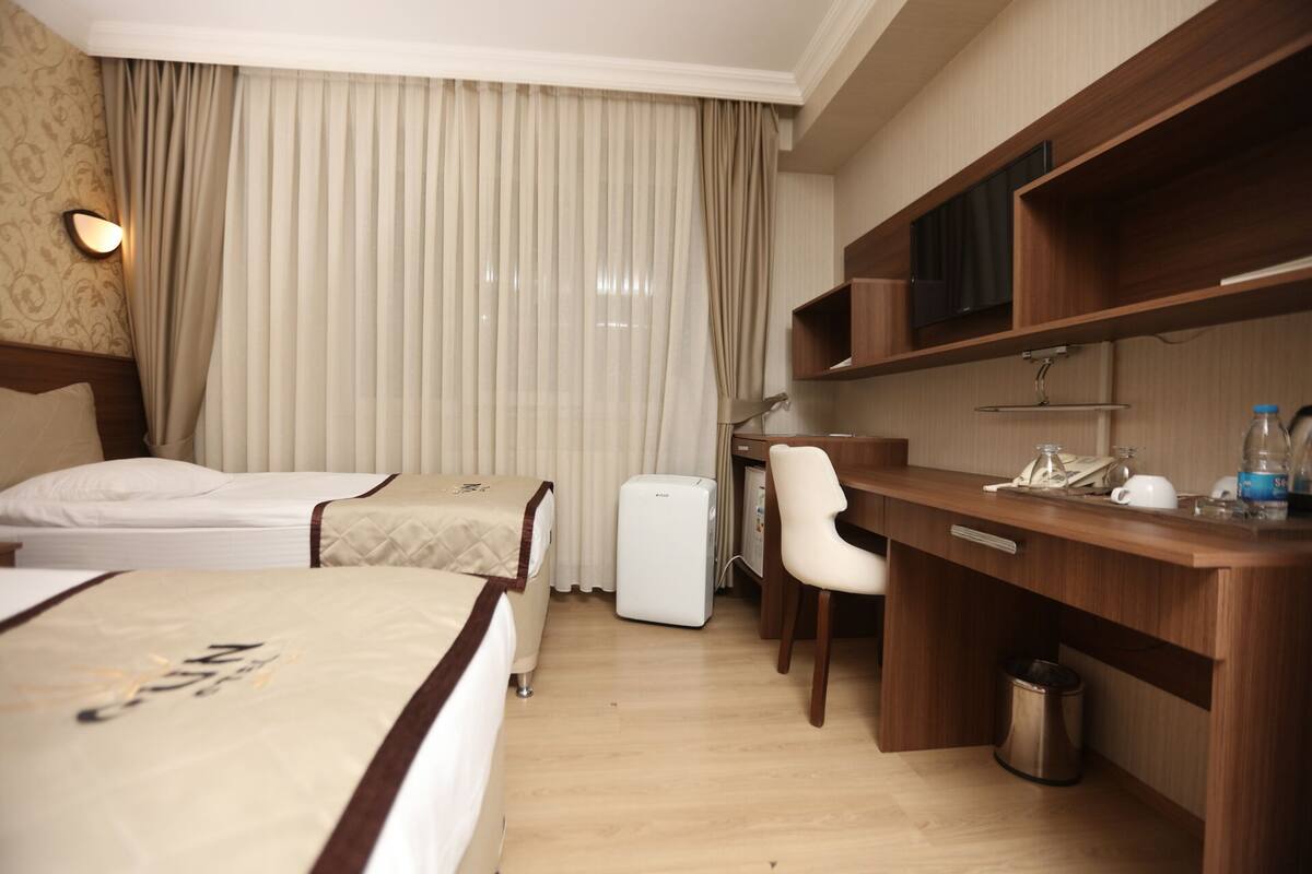 Ein Hotelzimmer mit zwei Betten, einem Schreibtisch, einem Stuhl, einem Fernseher und einer Minibar.